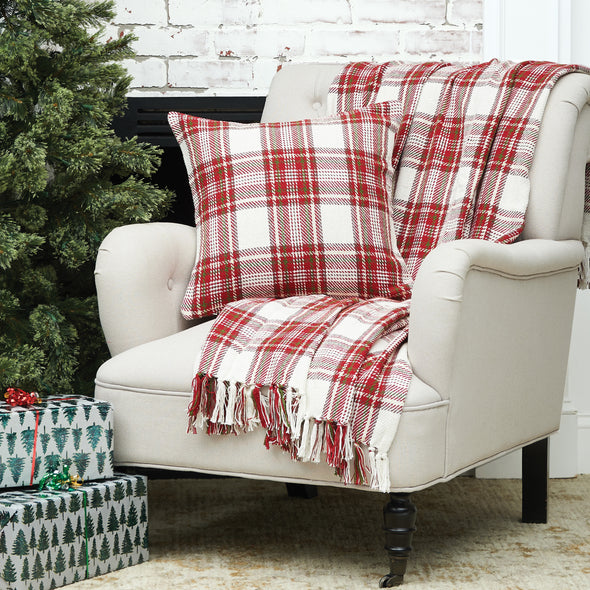 woven pillow with a red and white plaid design with a matching throw on a chair next to a Christmas tree and presents