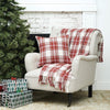 red and white woven throw with tassel edges on a chair with a matching pillow next to a tree and presents