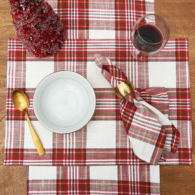 woven red and white plaid table linens on a wood table surrounded by a wine glass and holiday decor