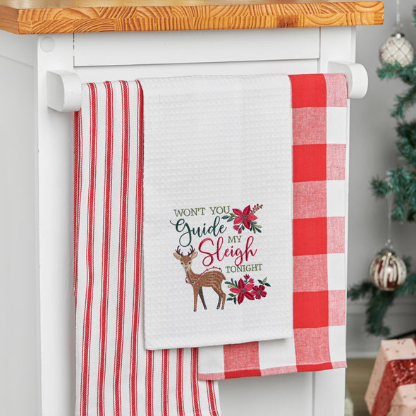 waffle weave towel with the phrase won't you guide my sleigh tonight in different font styles nestled between an adorable reindeer and red flower arrangements hanging from a kitchen counter