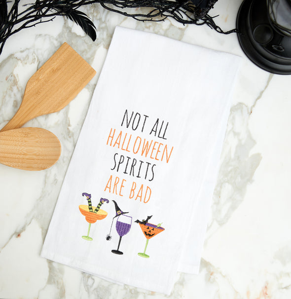 Flour sack kitchen towel with the saying "Not all Halloween spirits are bad" embroidered in black and orange. Styled on a marble countertop.