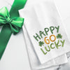 embroidered waffle weave towel with the words Happy Go Lucky surrounded by two clovers on a marble counter next to a green ribbon