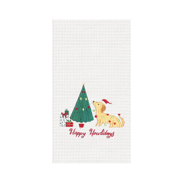 happy howlidays kitchen towel, dog putting ornaments on a tree on a white towel 