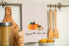 happy thanksgiving french knot kitchen towel hung from a kitchen utensil bar.
