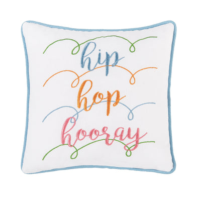 Embroidered with the words "hip hop hooray" a colorful pastel palette, A fun mix of bold and whimsical fonts stand out against the white ground. Finished with a blue piped border and pastel spiral accents across the pillow.