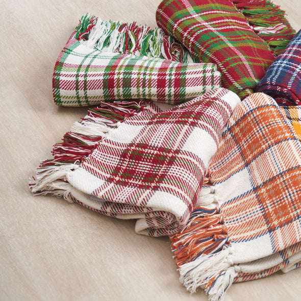 collection of woven holiday and winter throws with plaid designs and tassel edges arranged in a circular pattern