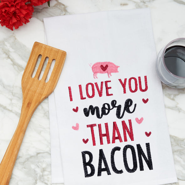 flour sack towel with the phrase I love you more than bacon surrounded by pink and red hearts on a marble counter