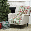 red green and white plaid woven throw with tassels on a chair next to a tree and presents