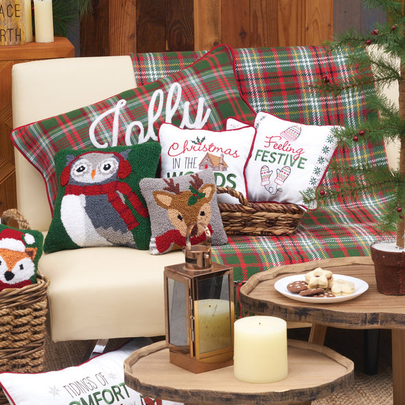 woodland Christmas creatures on pillows and throws sitting on a couch in a festive winter scene