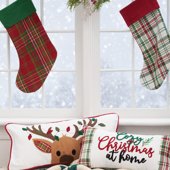 plaid stockings in front of a snowy window above Christmas pillows