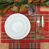 woven table linens with a red background and white and green accents in the plaid design on a wood table next to foliage