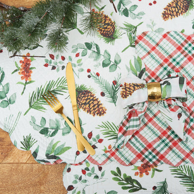 watercolor inspired foliage and pinecones on quilted table linens on a wood table