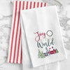 waffle weave towel with the phrase Joy to the World nestled between a wreath and above a snow covered town decorated for the holidays on a marble countertop