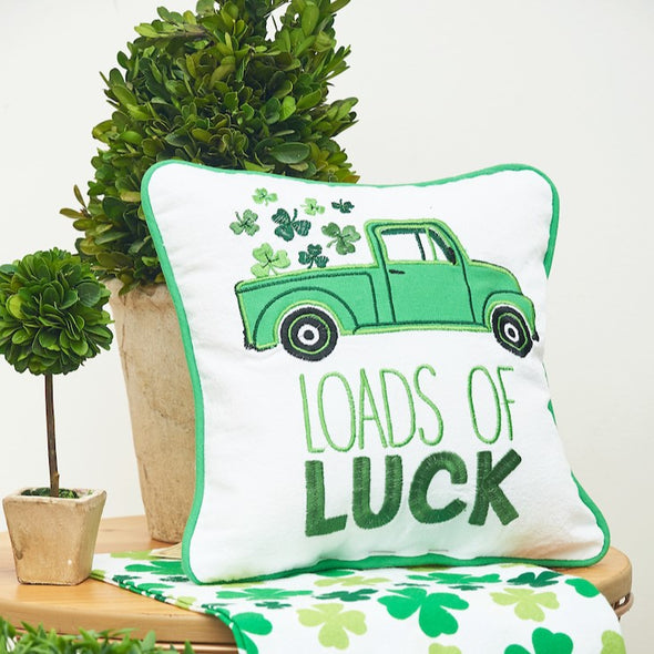loads of luck pillow on a table with a plant and shamrock towel