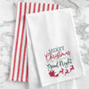 waffle weave towel with the phrase Merry Christmas to All & To All a Good Night in different fonts above Santa in his sleigh flying with his reindeer on a marble countertop