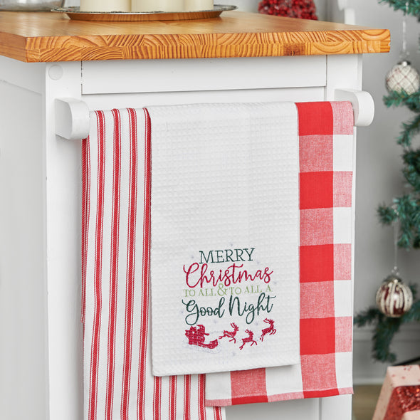 waffle weave towel with the phrase Merry Christmas to All & To All a Good Night in different fonts above Santa in his sleigh flying with his reindeer hanging from a kitchen countertop