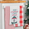 embroidered flour sack towel with the phrase Merry Everything and Happy Always above a polar bear wearing winter gear hanging from a kitchen countertop