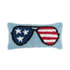 a hooked pillow featuring a light blue background and a pair of sunglasses with one side featuring blue with white stars and the other with red and white stripes to resemble the American flag.