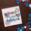 shelf block with the words peace love america surrounded by patriotic motifs on a wood background surrounded by red white and blue stars