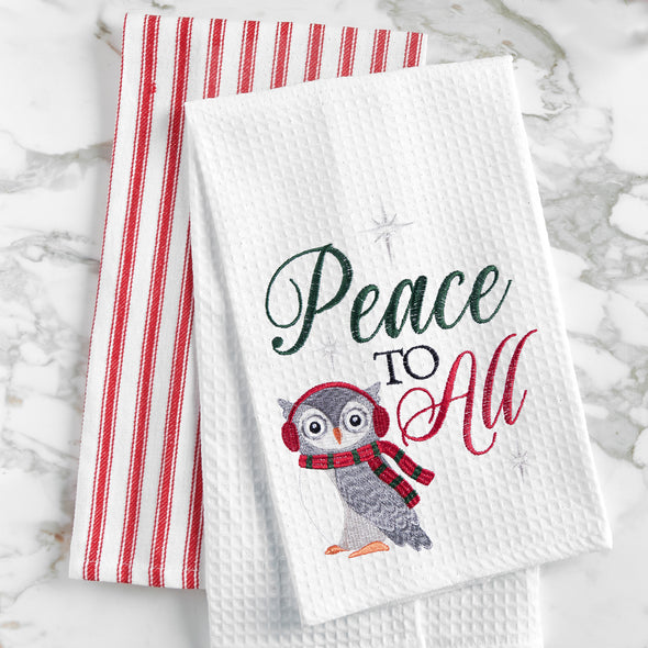 waffle weave towel with an owl bundled in winter gear next to the phrase peace to all on a marble countertop