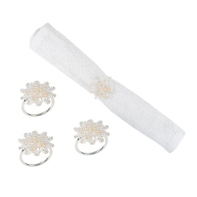 snowflake shaped napkin rings with imitation pearls decorating the tops - one wrapped around a white napkin