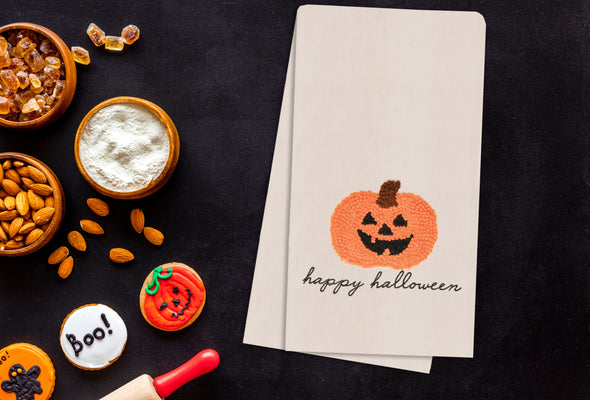 pumpkin french knot kitchen towel styled on a halloween themed flatlay
