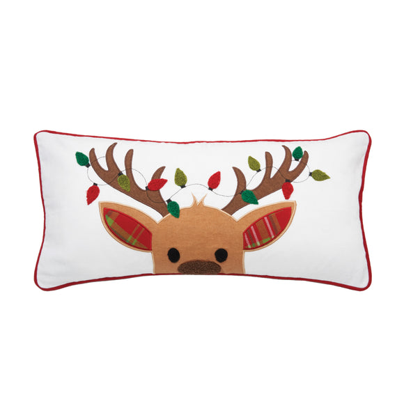 applique and tufted white pillow with a reindeer peeking over the bottom that has Christmas lights throughout its antlers