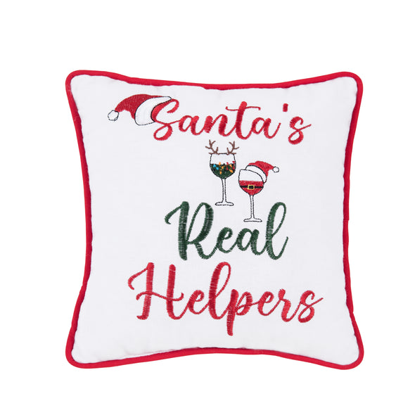 white pillow trimmed in red with the words Santa's real helpers embroidered in a flourishing script. two wine glasses decorate the pillow - one dressed up with antlers and the second glass with a Santa hat