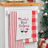 embroidered flour sack towel with the phrase Santa's real helpers above two glasses of holiday decorated wine hanging from a kitchen countertop