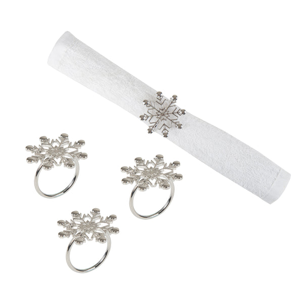 silver napkin rings shaped like snowflakes - one wrapped around a white napkin