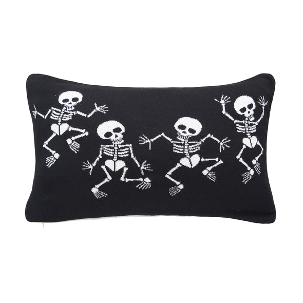 reversible knitted pillow featuring dancing skeletons. one side features skeletons with white bones on a black background while the reverse features the opposite.