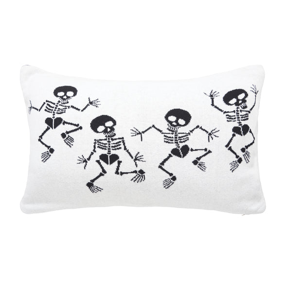 reversible knitted pillow featuring dancing skeletons. one side features skeletons with black bones on a white background while the reverse features the opposite.