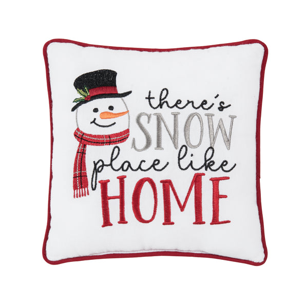 white pillow trimmed in red with the embroidered phrase there's snow place like home next to a snowman with a top hat and scarf