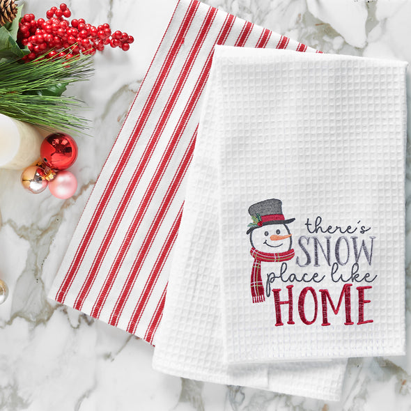 waffle weave towel with a snowman wearing a top hat and scarf next to the phrase there's snow place like home on a marble countertop