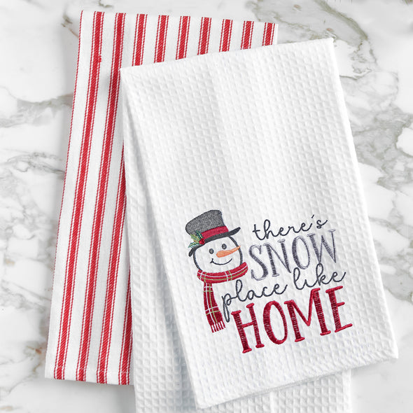 waffle weave towel with a snowman wearing a top hat and scarf next to the phrase there's snow place like home on a marble countertop