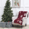 knitted throw with a red and black buffalo check and white snowflakes on a chair next to a tree and presents