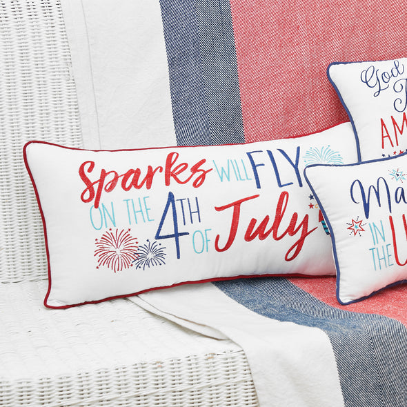 an embroidered pillow trimmed in red with the phrase sparks will fly on the 4th of july surrounded by bursting fireworks and sparklers next to other patriotic gift pillows