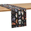 black table runner with mystical decorative elements including tarot cards, crystal ball, skulls, and other Halloween inspired motifs