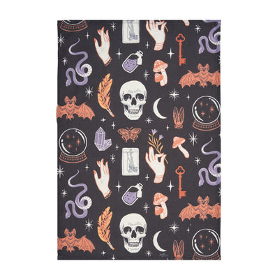 black printed kitchen towel with mystical motifs including skulls, potion bottles, snakes, bats, and crystal balls