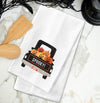 Spooky Pumpkin Truck kitchen towel styled on a marble countertop.