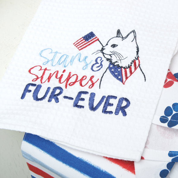 embroidered waffle weave towel with a cat proudly wearing a patriotic bandana scarf and holding a flag in its mouth with the words Stars & Stripes Fur-Ever surrounded by other patriotic kitchen towels