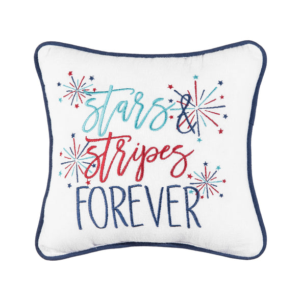 an embroidered pillow with blue and red flourishing text on a white background surrounded by bursts of red and blue fireworks and trimmed in a complementary blue