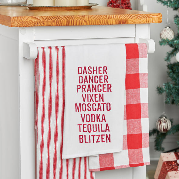 embroidered flour sack towel listing some of Santa's famous reindeer along with names of popular liquors in red embroidery hanging from a kitchen countertop