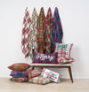 collection holiday winter woven throws with plaid designs hanging on hooks on a wall above coordinating plaid woven pillows