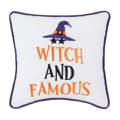 embroidered white mini pillow with the phrase witch and famous topped with a witches' hat and two stars where the eyes would be if a person was wearing the hat