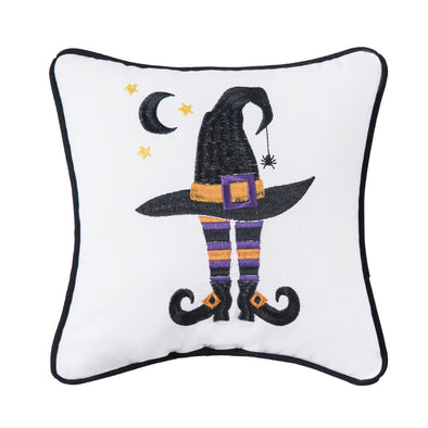 embroidered white mini pillow with a witches' hat on top of striped leggings and buckled boots underneath a black half moon and stars. 