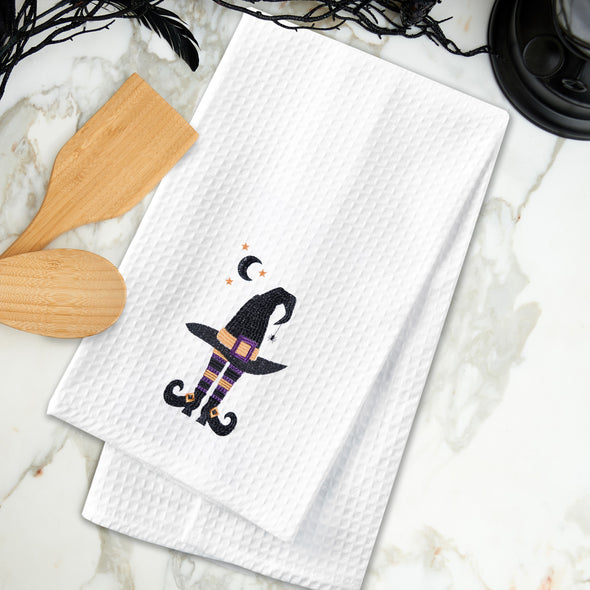 embroidered waffle weave towel with a black witches' hat and legs next to a halfmoon and stars on a marble counter