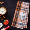 woven orange black and white plaid kitchen towel next to Halloween candy