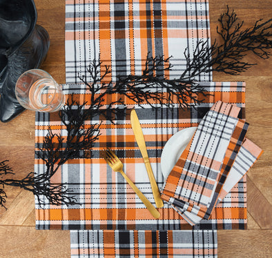 woven orange black and white plaid table linens on a wood table surrounded by Halloween decor