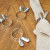 silver metal bunny ears napkin rings laid on a dining room table